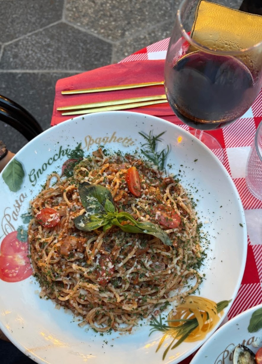 Spaghetti bolognaise servis en terrasse avec un verre de vin rouge